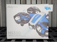 Box of Holyton HS330 quadcopter showing branding and model with obstacle avoidance and remote control features.