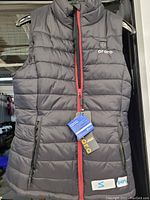 Front view of black Ororo heated vest with red zipper, showing brand logo and tags attached.