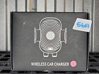 Photo of the sealed black box containing the wireless car charger and phone stand. The box shows a white line illustration of the charger and the words 'Wireless Car Charger' with a pink dot.