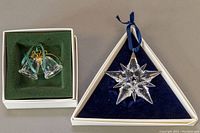 Pair of Swarovski Austrian crystal Christmas ornaments shown in their original boxes, one star and one pair of bells.