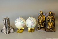 Photo showing all three pairs of bookends: stone, globe, and bronze figurines