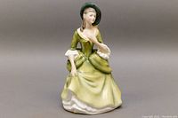Front side view of Royal Doulton porcelain figurine 'Sandra' showing the figure in green dress with bonnet and white lace