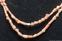 Close-up of the irregular natural pink coral beads on the double-strand necklace, showing bead color and shapes.