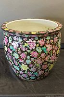 Front view of the large hand painted fish bowl planter pot showing intricate floral pattern on black background.