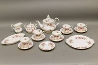 Full group shot showing teapot, sugar bowl, creamer, cake plate, under-plate, cups and saucers
