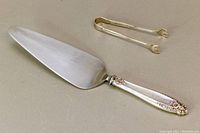 Cake cutter showing flat metal blade with sterling silver handle decorated with flowers
