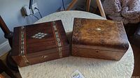 Two wood boxes on a round table, clearly showing mother of pearl inlays and wood veneer patterns.