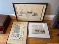 Three framed art prints set against a wall, showing varying sizes and visible damage to frames and mats.