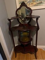 Full frontal view of the wood display cabinet showing overall form, shelves and base.