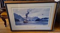 Framed limited edition print of steamboat on lake, wide angle shot showing full frame and chair beside it