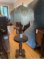 Full view of the wooden side table floor lamp with a crocheted floral-patterned lampshade in a room setting.