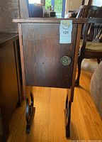 Side view of wooden smokers stand showing tarnished metal knob and wood finish with surface wear.