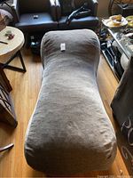 Full view of the gray upholstered chaise lounge showing its ergonomic curved shape and smooth fabric surface.