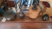 Black ceramic incense bowl with carved frog lid on table with other items