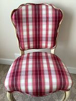 Front view of the chair showing red plaid fabric upholstery and scalloped backrest