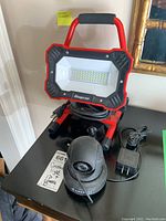 Photo of Snap-on work light and Amcrest IP camera on a black table showing full items and cords.