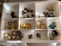 Tray with multiple pairs of earrings in various designs including Mexican silver, colorful beads, turquoise, and gold-tone metal with pearls