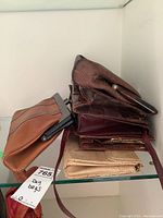 Shelf display of six vintage handbags stacked horizontally showing different snakeskin textures and colors including brown, burgundy, and gold.
