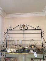 Black metal display rack holding assorted silver-plated serveware