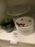 Photo of Limoges porcelain plates stacked next to green glass nappies and white pierced edge cake plate.