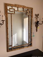 Front view of mirror showing overall gilt faux bamboo frame and Greek key design