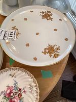Top down view of the round French footed plate with gold floral motifs and gold rim, showing the plate's surface and pattern