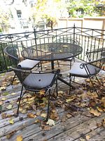 Full set on wooden deck covered with fallen leaves, showing table and four chairs