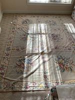 Full view of the rectangular tapestry rug laid out on a carpeted floor. Shows overall floral design and size.
