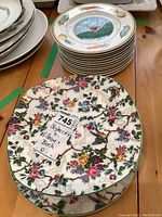 Stack of twelve white Villeroy & Boch lunch plates with painted country bird and vegetable design, plus a StyleCraft Midwinter Bird Chintz floral bird plate on top