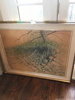 Full view of painting leaning against a wall/granite floor showing tree and roots artwork with frame detached