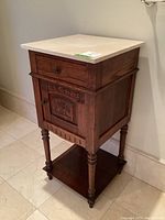 View of the antique carved wooden end table with separate marble top and ornate carved details, showing turned legs and lower shelf