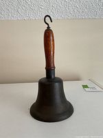 Front view of the cast iron cowbell showing wooden handle and metal hook