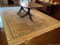 Full view of wool carpet under dining table showing cream ground, border design and fringed edges