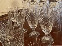 Crystal glasses grouped on a dark wood surface, showing cut and etched designs with a clear focus on patterns and the glass bases.