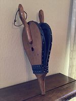Front and side views showing overall wooden structure, handles, and leather sides with brass rivets.