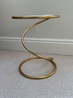 Side view of the brass corkscrew frame of the table showing the spiral metalwork and round brass base ring.