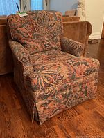 Front angle view showing tapestry fabric with floral and leaf pattern, rolled arms, and skirted base.