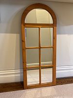 Full front view of arched-top mirror leaning against wall