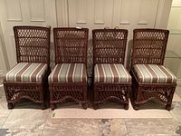 Front view of four wicker dining chairs showing striped upholstered seats and woven backrests.