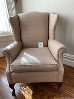 Front view of wing back chair showing the patterned fabric upholstery and cabriole legs