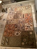 Full view of the carpet showing the entire patchwork design on stone tile floor.
