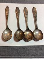Four vintage spoons arranged side-by-side, showing the obverse side with Mickey Mouse embossed handles.