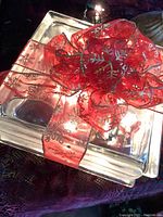 Top angled view of the glass block showing the red snowflake ribbon and how it is tied into a large decorative bow, with lights illuminating inside the block.