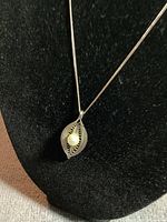 Front view of silver filigree pendant with pearl on black necklace display stand