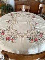 Full view of the oval tablecloth spread on a dining table, showing overall design and size.