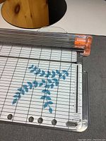 Fiskars paper cutter showing the measuring grid and blue leaf patterned paper underneath the cutting area.