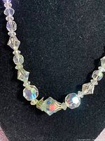Close-up of the central section of the necklace showing large faceted Austrian crystals framed by sterling silver floral pieces, against a black velvet background, highlighting the sparkling and light-catching properties.