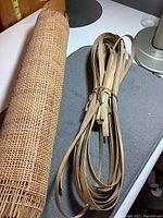 Rolled cane webbing and bundle of wicker strips on a surface