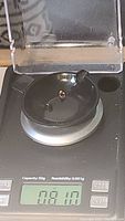 Two small faceted multicoloured tourmaline gemstones being weighed on a scale showing 0.81 carats.
