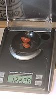Photo of two polished orange Carnelian gemstones on a digital scale showing a total weight of 12.23 carats.
